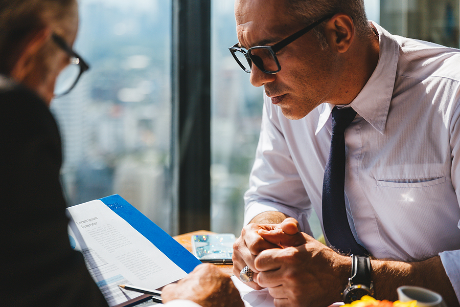 Business professionals discussing strategies around a table with a list of top ten ways to safeguard a deal.